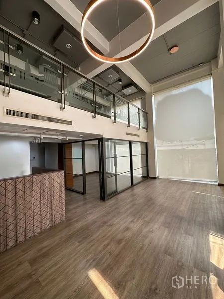 Office Space for rent in Pathum Wan, Bangkok - Spacious double-volume office with mezzanine, glass partitions and a modern circular chandelier.