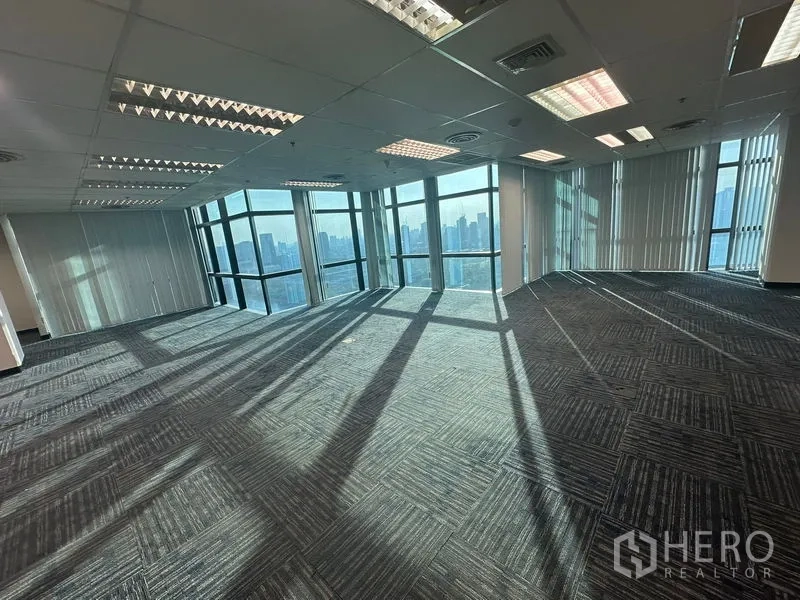 Office Space for rent in Watthana, Bangkok - Bright open workspace with wraparound windows casting long afternoon shadows.