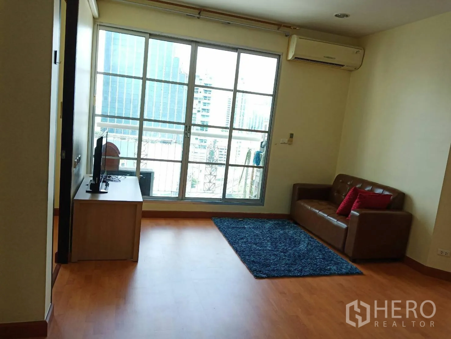 公寓 出租在Khlong Toei, Bangkok - 明亮客厅，落地推拉门通往阳台，城市景观，配电视柜与空调