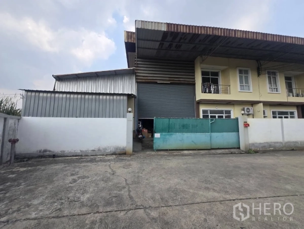 Factory for rent or sale in Mueang Samut Sakhon, Samut Sakhon - Front facade of factory featuring large roller shutter, gated entrance and parking apron.