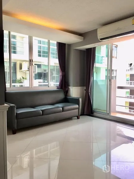 Condominium for rent in Khlong Toei, Bangkok - Corner lounge with sofa beside balcony and wide windows.