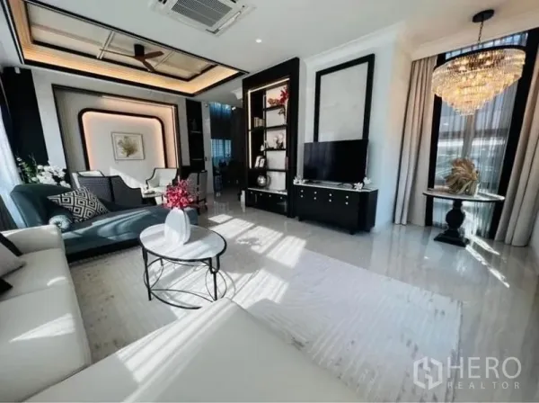 Detached House for rent or sale in Watthana, Bangkok - Bright living room with marble floors, chandelier, TV wall and floor-to-ceiling windows.