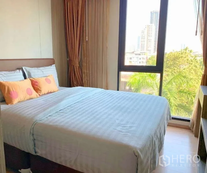 Condominium for rent - Cozy bedroom with double bed and floor-to-ceiling window offering city and tree views.
