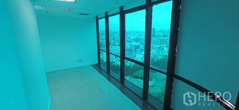 Office Space for rent in Huai Khwang, Bangkok - Narrow windowed room with full-height glass showcasing a broad city skyline view.