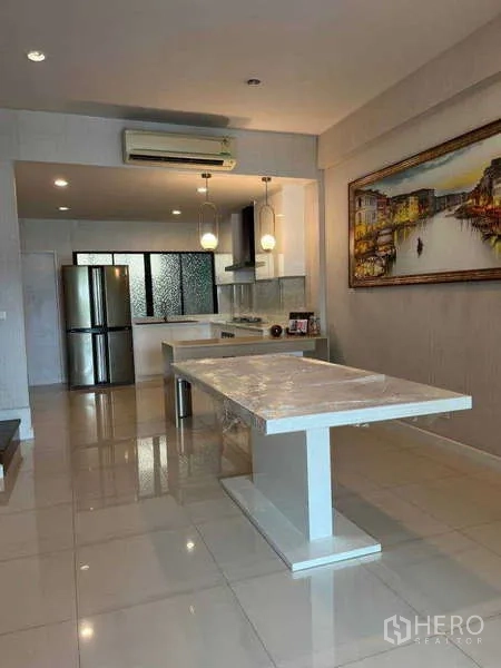 Townhouse for rent in Khlong Toei, Bangkok - Dining space facing the kitchen with marble-top table, stainless fridge, and ceiling lights.