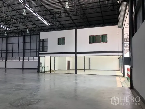 Warehouse for rent in Bang Phli, Samut Prakan - Interior view showing attached two-storey office block with glass entrance beside the warehouse floor.