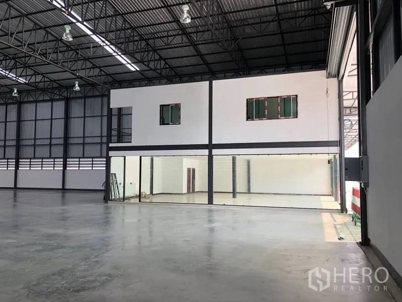Warehouse for rent in Bang Phli, Samut Prakan - Interior view showing attached two-storey office block with glass entrance beside the warehouse floor.