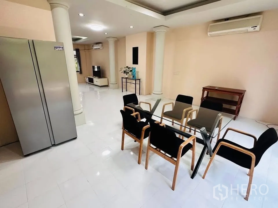 Townhouse for rent - Dining area with a glass table and six chairs beside decorative columns and a large fridge.