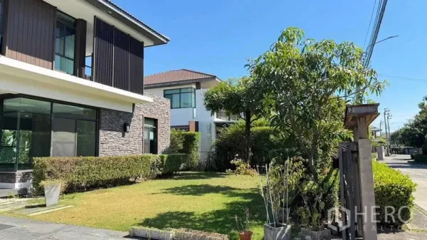 Detached House for sale in Bang Kapi, Bangkok - Front garden with trimmed hedges and trees beside a contemporary house facade.