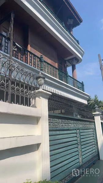 Townhouse for rent in Khlong Toei, Bangkok - Front elevation with green gated fence and wraparound balconies.