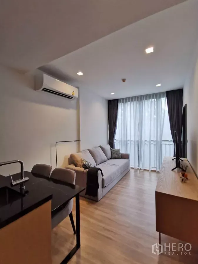 Condominium for rent in Watthana, Bangkok - Living‑dining area facing the balcony next to a compact kitchen peninsula.