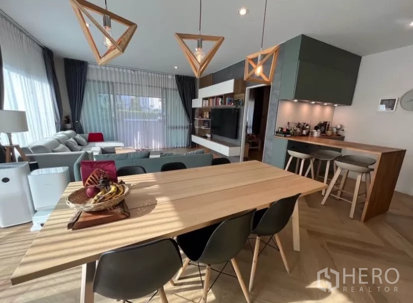 Detached House for rent in Prawet, Bangkok - Close view of a long wooden dining table and breakfast bar in the open-plan space.