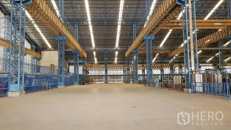 Factory for rent in Mueang Samut Sakhon, Samut Sakhon - Spacious factory bay featuring overhead crane girders, bright lighting, and clear floor area.