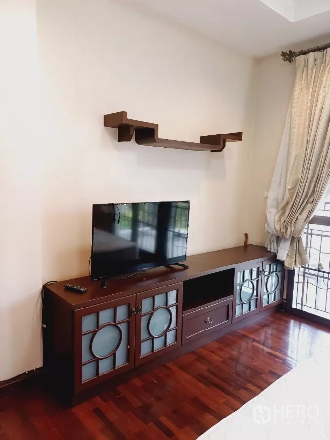 Detached House for rent or sale in Mueang Nonthaburi, Nonthaburi - Built-in TV console and wall shelf in a bedroom with wooden floor and curtains.
