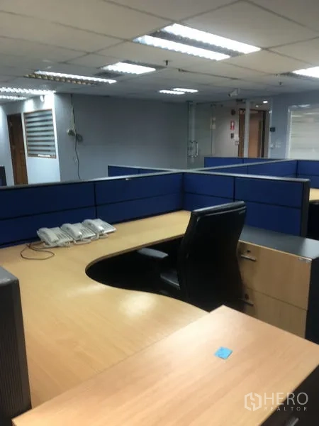 Office Space for rent - Reception or workstation with L-shaped desk and blue dividers in an open office zone.