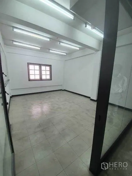 Shophouse for rent in Bang Rak, Bangkok - Bright office-style room with a glass wall, window and overhead fluorescent lighting.