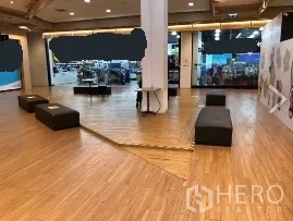 Retail Space for rent in Khlong Toei, Bangkok - Open-plan retail area with wood-look flooring, central pillar, benches and bright mall shopfronts near BTS Thong Lo.