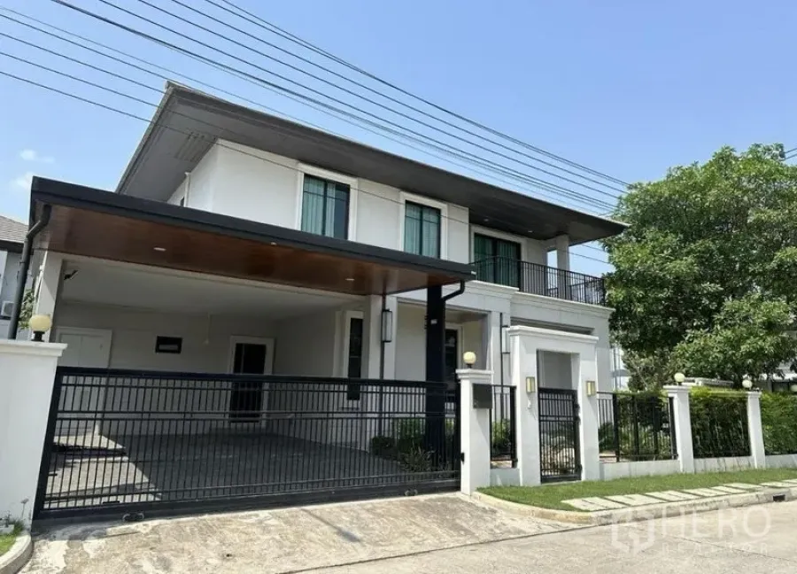 Detached House for sale in Prawet, Bangkok - Front exterior of the detached home with high fence and double carport.