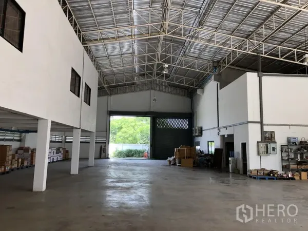 工厂 出租或出售在Lat Lum Kaeo, Pathum Thani - 仓库大厅朝向大型装卸卷闸门，可见储物区与顶灯。