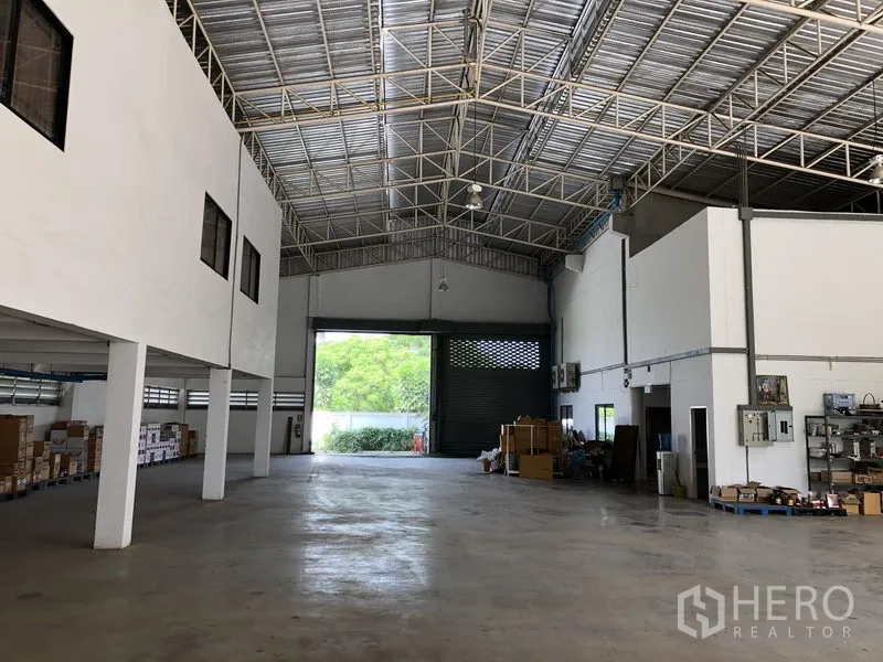 工厂 出租或出售在Lat Lum Kaeo, Pathum Thani - 仓库大厅朝向大型装卸卷闸门，可见储物区与顶灯。