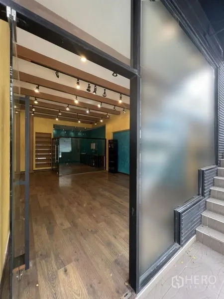 Retail Space for rent in Watthana, Bangkok - View from the entrance into the shop showing frosted glass panel, wood floors, and street access.