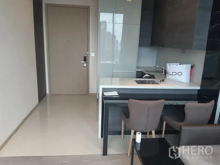 Condominium for rent or sale in Watthana, Bangkok - Modern kitchenette with island breakfast bar and two dining chairs.