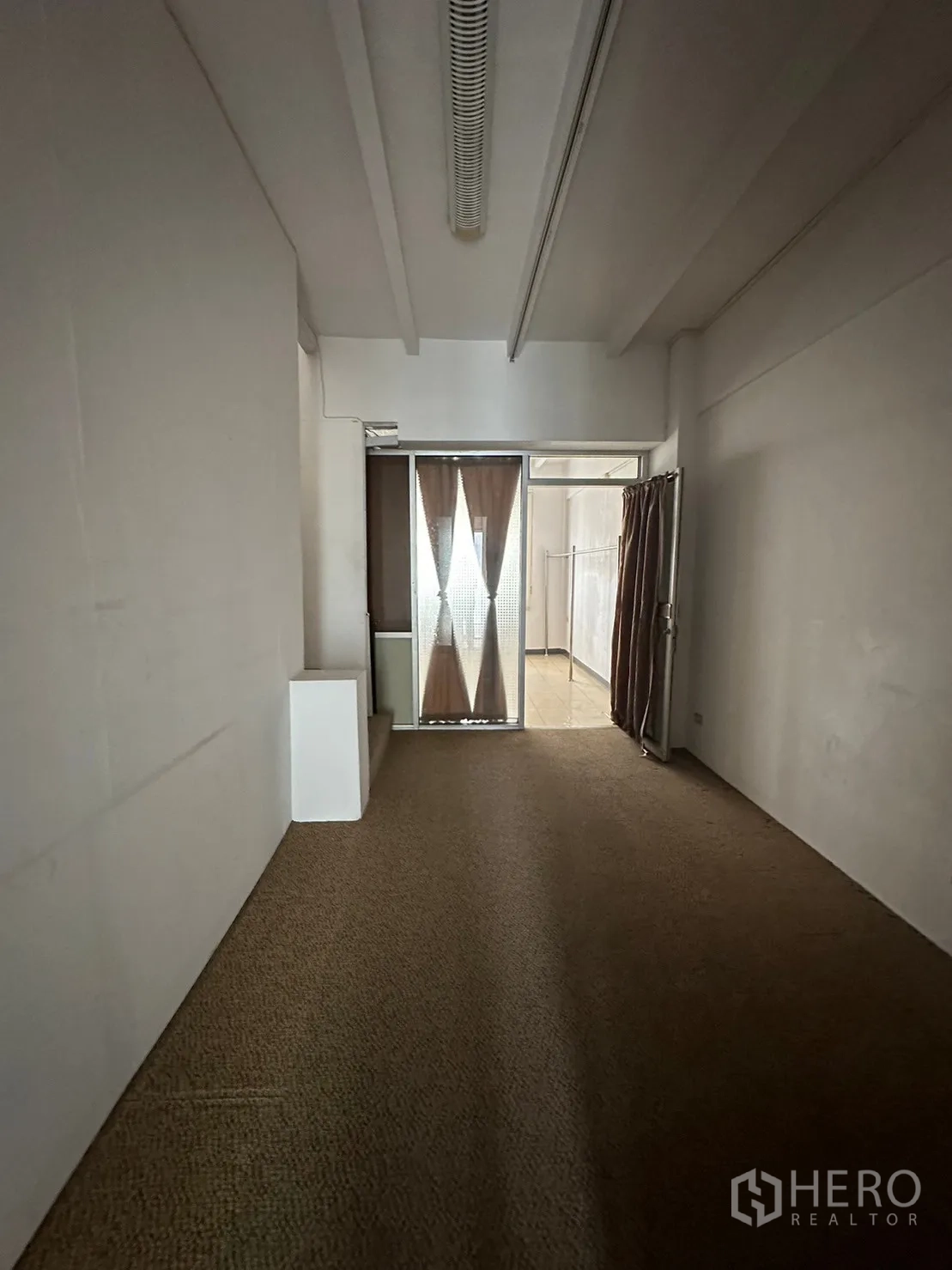 Retail Space for rent in Watthana, Bangkok - Long narrow room with carpet and a glass door at the end