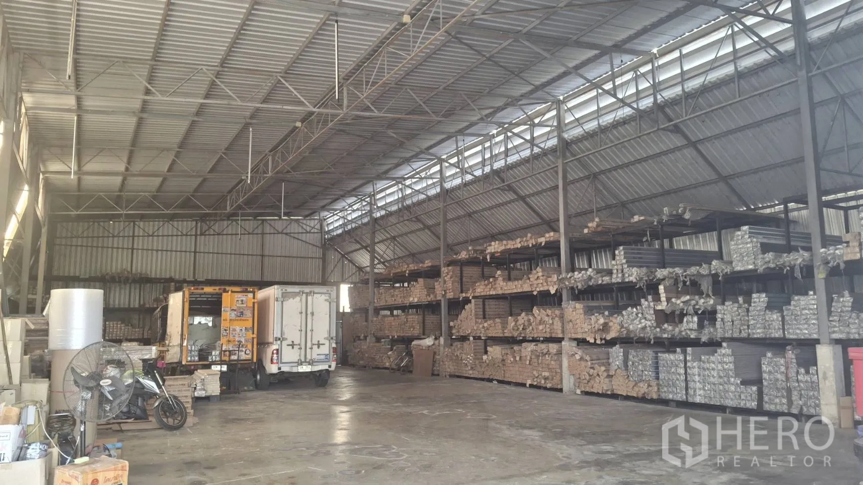 仓库 for sale in Lam Luk Ka, Pathum Thani - 仓库内部空间宽敞，钢桁架高挑屋顶，混凝土地面，宽阔卡车装卸区与多排重型货架。