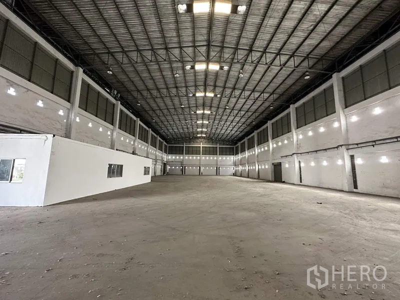 工厂 出租在Bang Bua Thong, Nonthaburi - 宽敞厂房内部，高钢桁架屋顶、明亮照明与混凝土地面。