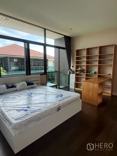 Detached House for rent in Bang Kapi, Bangkok - Sunlit bedroom with double bed, built-in shelves, desk and access to a balcony.
