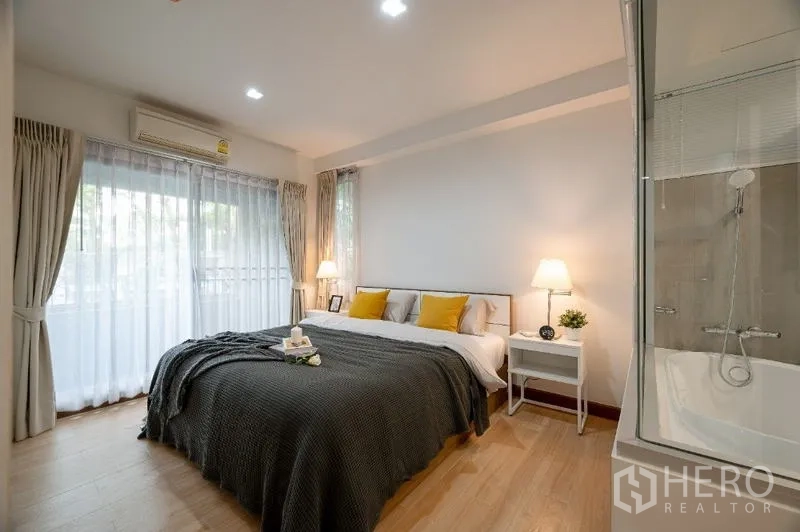 Condominium for sale - Spacious master bedroom with floor-to-ceiling windows and adjacent bathtub behind glass partition.