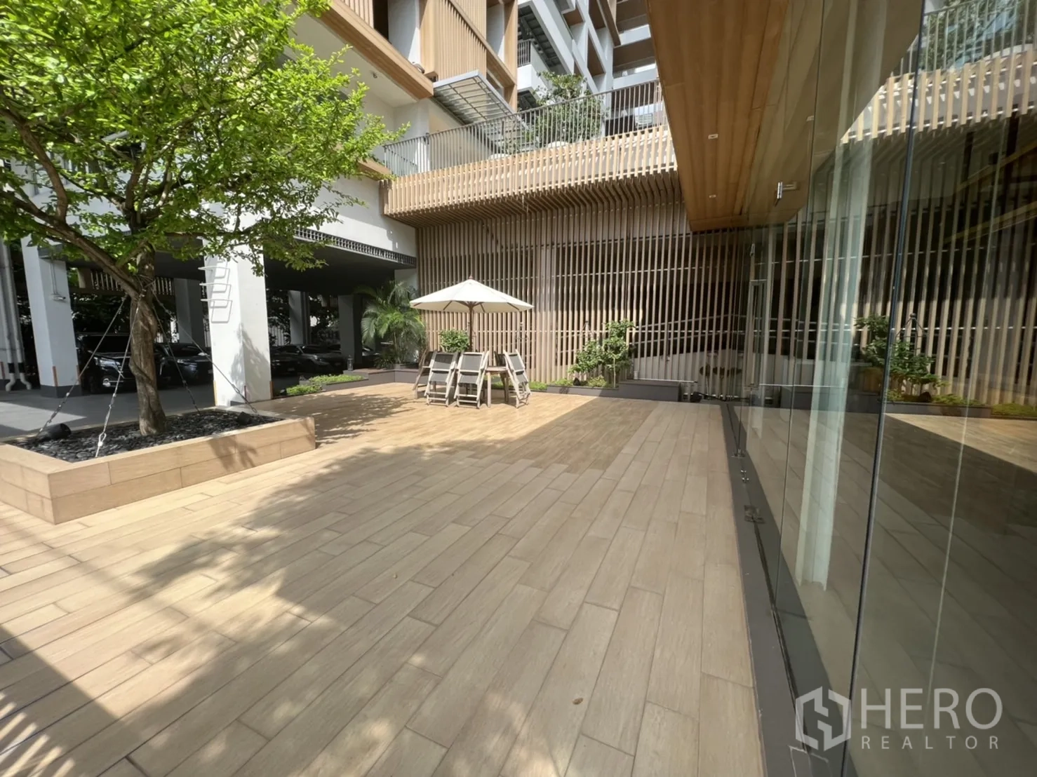 Retail Space for rent in Watthana, Bangkok - Outdoor terrace with wood-look tiles, umbrella table, glass storefront and planted tree.