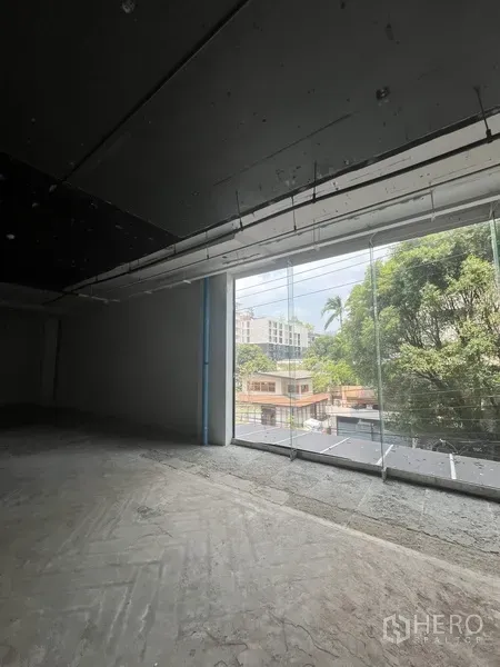 Retail Space for rent - Retail space with a wide floor-to-ceiling window bringing natural light and views of trees and low-rise buildings.