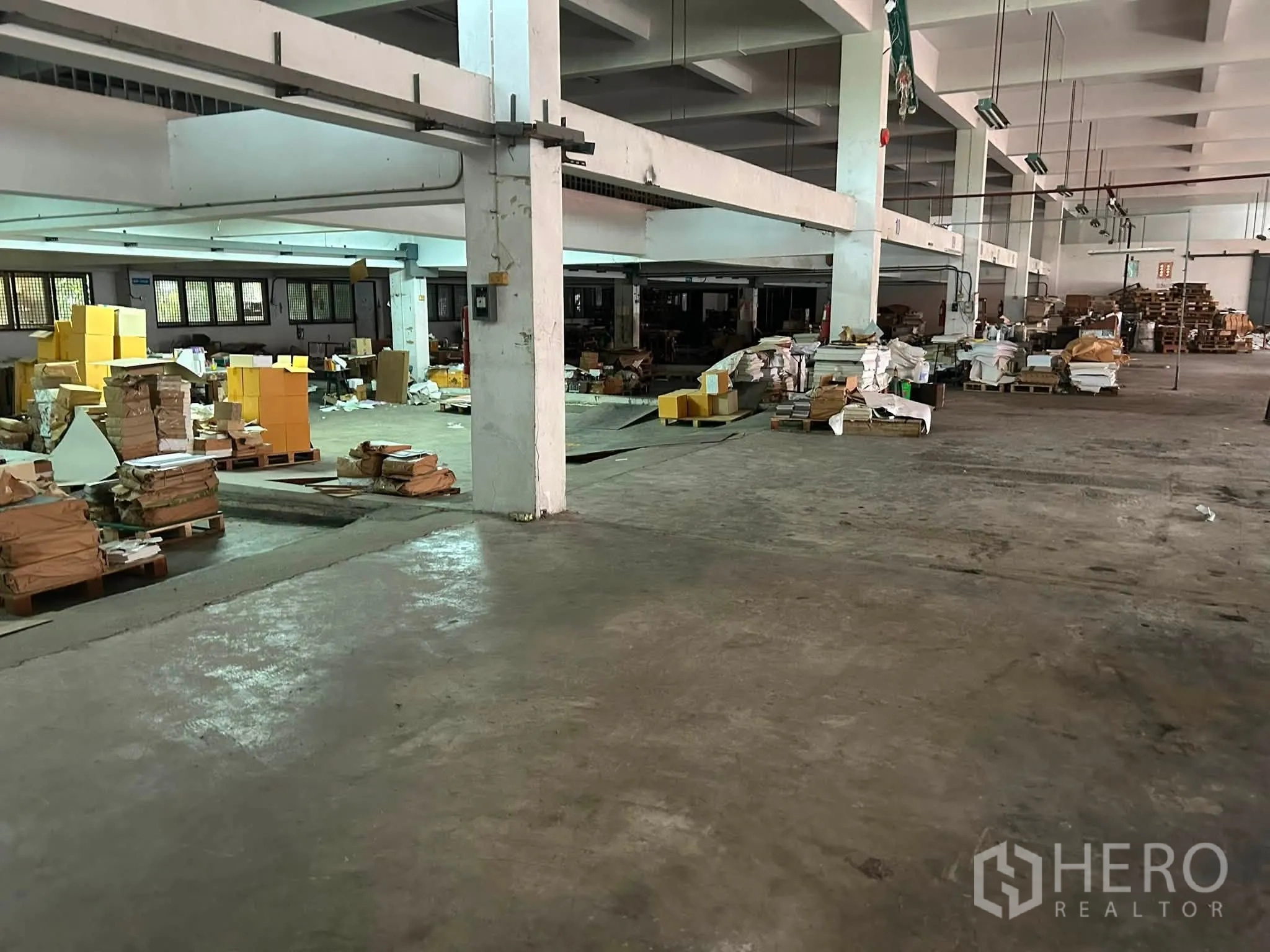 Warehouse for rent in Phra Khanong, Bangkok - Storage zone with pallets and materials spread across a large warehouse floor with structural columns.