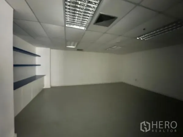 Office Space for rent - Compact meeting room with built‑in wall shelves and suspended ceiling lighting.