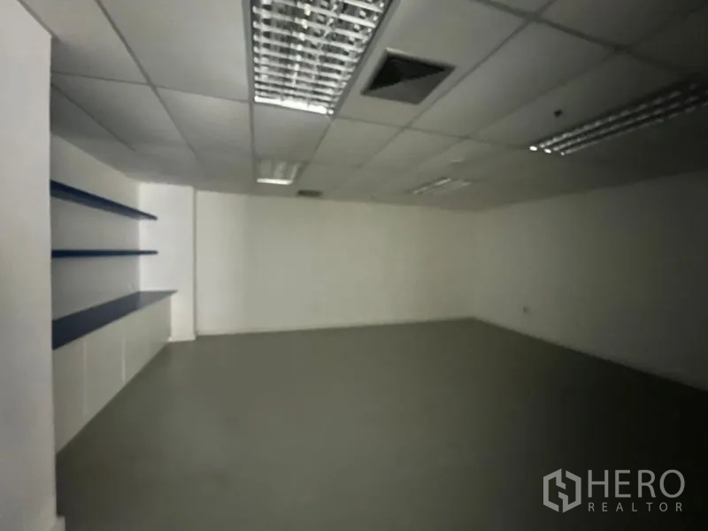 Office Space for rent - Compact meeting room with built‑in wall shelves and suspended ceiling lighting.