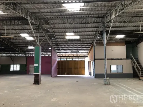 Warehouse for rent in Sai Mai, Bangkok - Warehouse hall with partitioned office, staircase to an upper room, and a large sliding entrance.