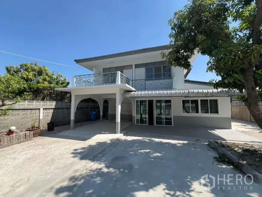 Detached House for rent in Bang Na, Bangkok - Exterior view of the detached house with balcony and a large paved outdoor area.