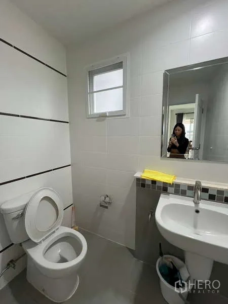 Detached House for rent in Bang Kapi, Bangkok - Downstairs bathroom with toilet, sink and wall mirror.