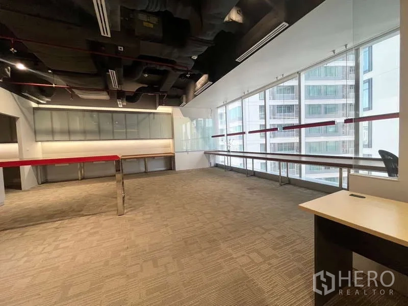 Office Space for rent in Watthana, Bangkok - Open-plan space facing neighboring towers through full-height glazing with long window desk.