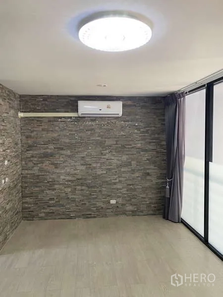 Home Office for rent or sale - Room featuring a stone-texture accent wall, air conditioner and sliding glass to balcony.