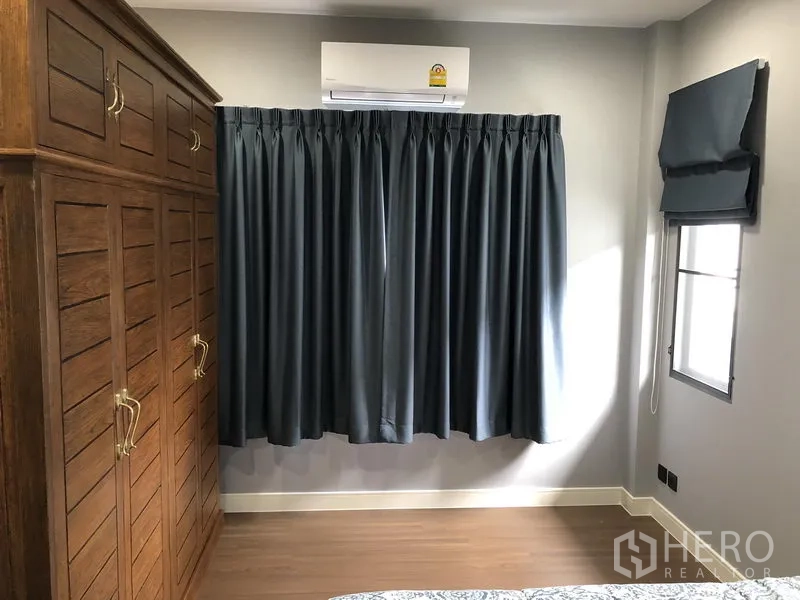 Detached House for rent in Bang Kapi, Bangkok - Bedroom corner with large wooden wardrobe, blackout curtains and air conditioning.