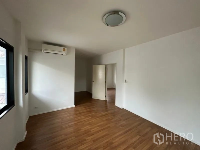 独立式住宅 出售在Bang Khen, Bangkok - 木地板卧室，装分体空调并有两扇窗。