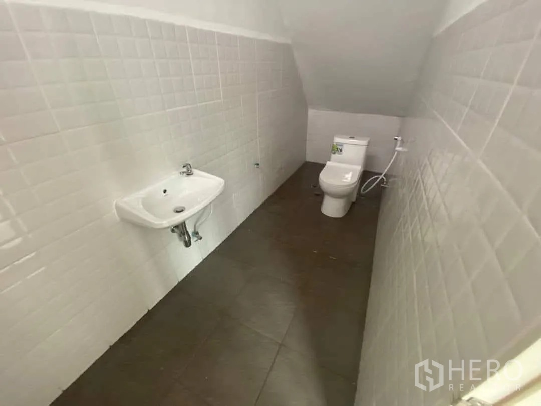 Factory for rent or sale in Mueang Samut Sakhon, Samut Sakhon - Clean tiled restroom with wall-mounted sink and toilet inside the factory.