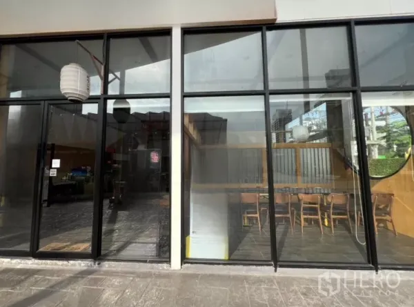 零售空间 出租在Watthana, Bangkok - 高挑玻璃店面，可见室内座位与悬挂灯笼。