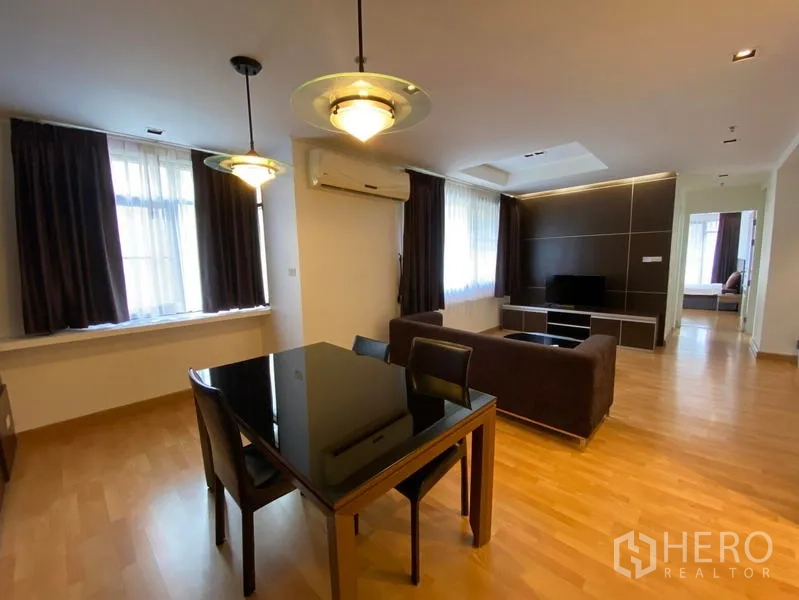 Condominium for rent in Khlong Toei, Bangkok - Bright open-plan living and dining area with wood floors, pendant lighting and large curtained windows.