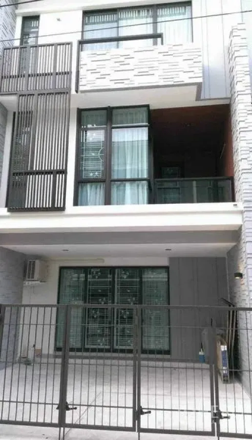 联排别墅 出租在Bang Phli, Samut Prakan - 现代三层联排别墅外立面，带可上锁前院车位、大窗与阳台。