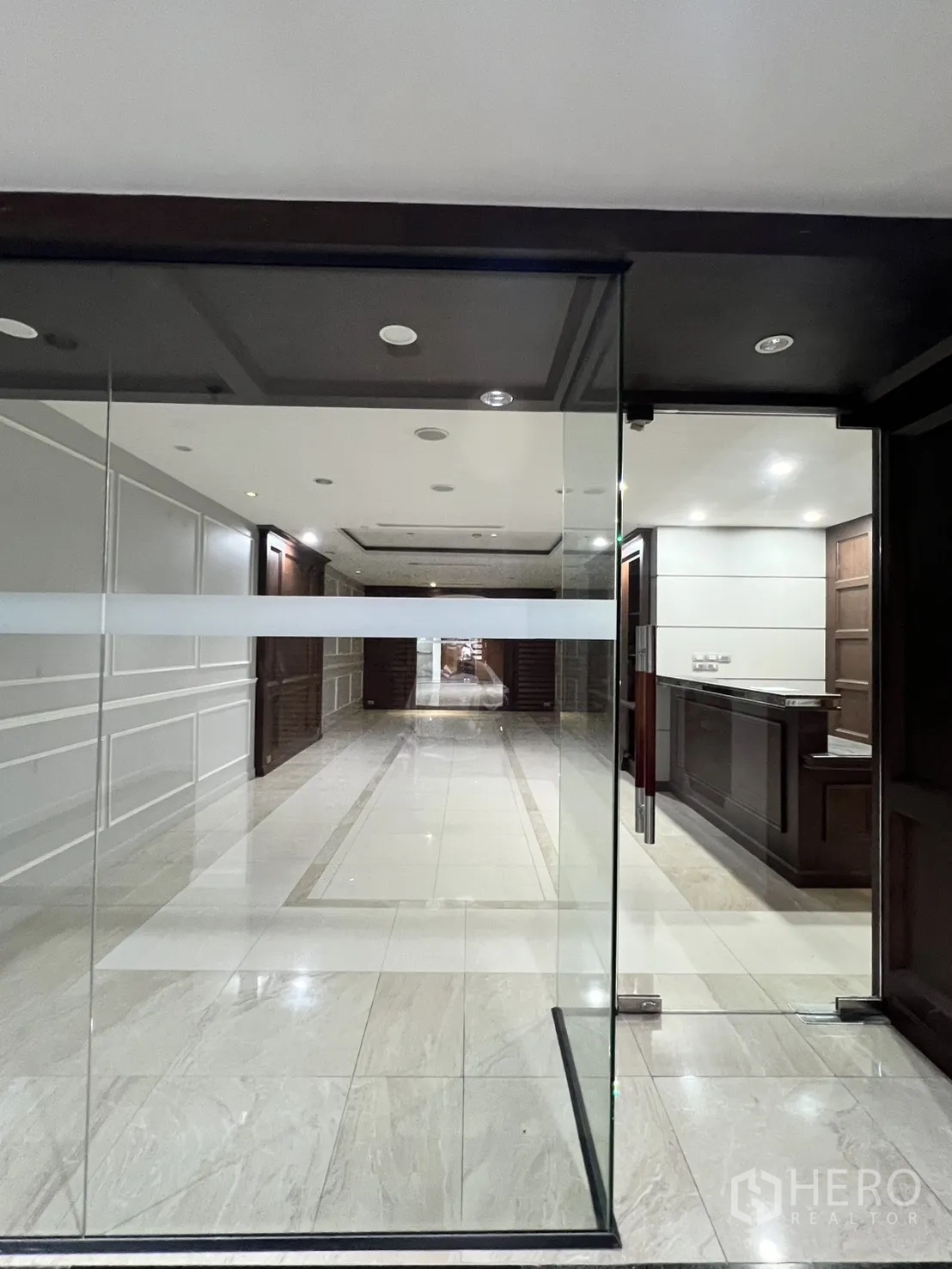 Office Space for rent in Watthana, Bangkok - Reception counter and corridor seen through a clear glass door.