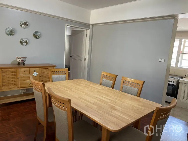 Condominium for rent in Watthana, Bangkok - Dining area with six-seat wooden table beside the kitchen.