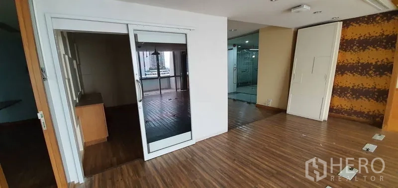 Office Space for rent in Watthana, Bangkok - Workspace with sliding door, patterned accent wall, and view toward the glass-fronted entry.